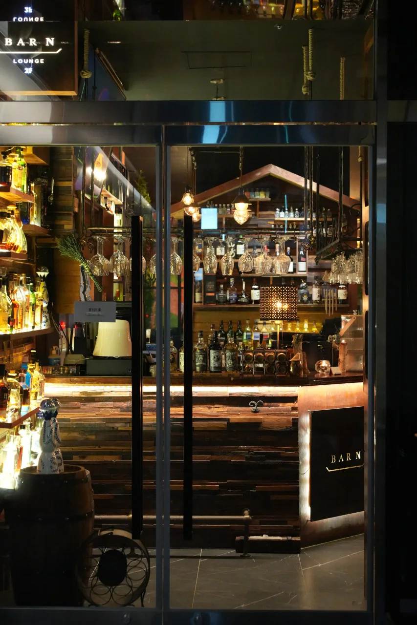 ガラス扉の向こうに見えるバーと「BARN LOUNGE」の看板